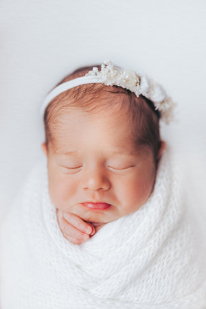 Newborn baby girl photographed in studio, on white background. Stylized and wrapped. Cute expression.の写真素材