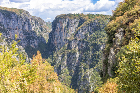 Majestic view of Vikos Gorge in Zagori, Epirus, Greece, one of the deepest canyons in the world. The scene captures dramatic cliffs, lush greenery, and rugged terrain under natural sunlight, offering a breathtaking perspective of this iconic hiking and adventure destination. Ideal for travel, nature, and landscape photography.の写真素材