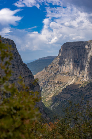 Majestic view of Vikos Gorge in Zagori, Epirus, Greece, one of the deepest canyons in the world. The scene captures dramatic cliffs, lush greenery, and rugged terrain under natural sunlight, offering a breathtaking perspective of this iconic hiking and adventure destination. Ideal for travel, nature, and landscape photography.の写真素材