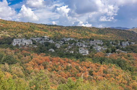 Picturesque view of Monodendri village in Zagori, Epirus, Greece, on a sunny yet cloudy autumn day. The scene showcases traditional stone houses, vibrant fall foliage, and the stunning mountainous landscape of the region. A perfect representation of Greeceâs rural charm and natural beauty, ideal for travel and landscape photography.の写真素材
