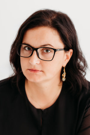 Studio portrait of a confident 40-year-old woman wearing an elegant black outfit and glasses against a clean white background. She exudes professionalism and sophistication, making the image ideal for business, corporate, fashion, and lifestyle concepts. Perfect for marketing, editorial, and commercial use.の写真素材