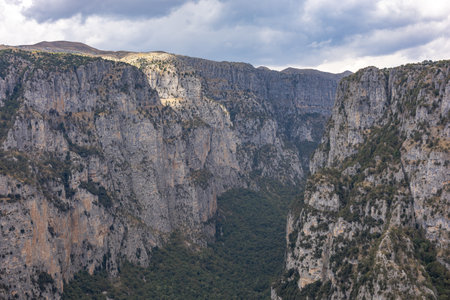 Majestic view of Vikos Gorge in Zagori, Epirus, Greece, one of the deepest canyons in the world. The scene captures dramatic cliffs, lush greenery, and rugged terrain under natural sunlight, offering a breathtaking perspective of this iconic hiking and adventure destination. Ideal for travel, nature, and landscape photography.の写真素材