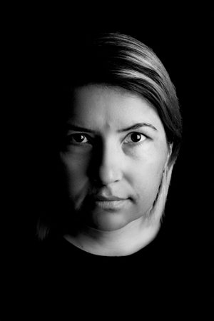 Studio portrait of a 40-year-old woman against a black background. Her confident expression and elegant presence create a timeless, professional imageの写真素材
