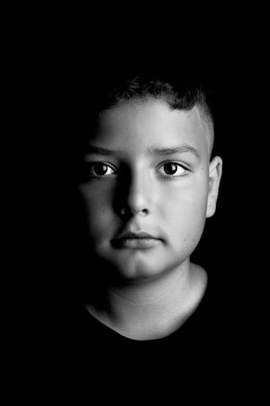 Studio portrait of a 10-year-old preteen boy against a black background.の写真素材