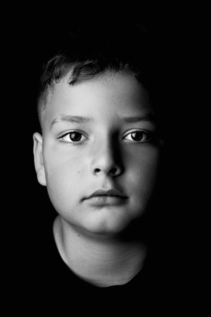 Studio portrait of a 10-year-old preteen boy against a black background.の写真素材