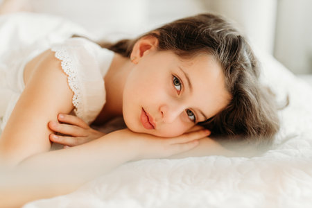 Studio portrait of a delicate girl in a festive Christmas setting. Surrounded by warm lights and holiday decorations, she exudes innocence and joy, capturing the magic of the season.の写真素材