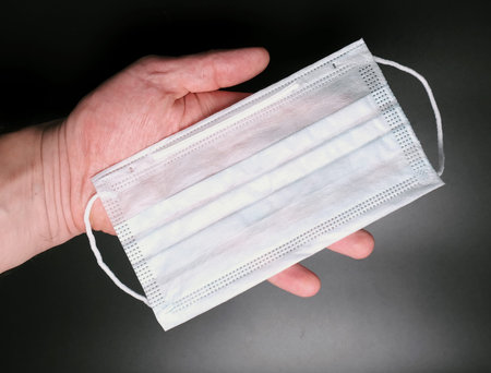 medical face mask in hand on black backgroundの写真素材