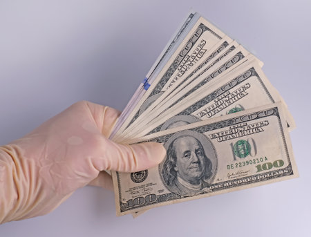 hand in latex gloves hold dollars moneyの写真素材