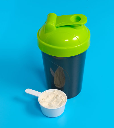 sport protein shaker cup with spoon on blue background