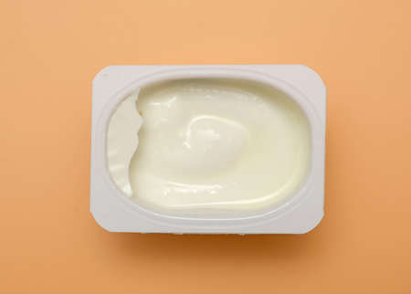 milk cottage cheese cream in plastic container on yellow backgroundの写真素材