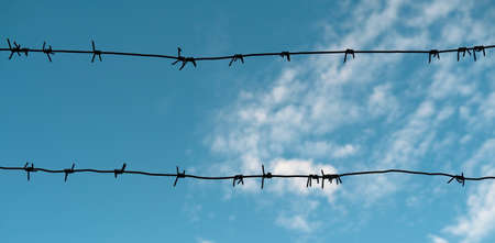 metal barbed wire fence on cloud blue sky backgroundの写真素材
