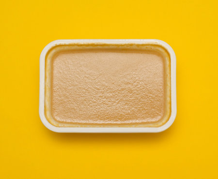 peanut nut paste butter in white plastic container on yellow background