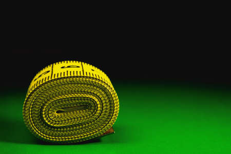 Dieting symbol of yellow measuring tape on green background.Yellow measuring tape.の写真素材