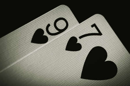 Poker background. Nine of hearts and seven of hearts on a black background, close up. Black and white photo.の写真素材
