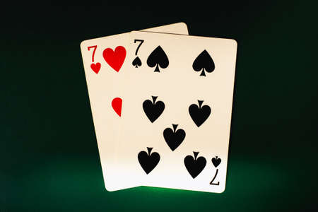 Seven of hearts and seven of spades. A pair of sevens on a black background, poker background.の写真素材