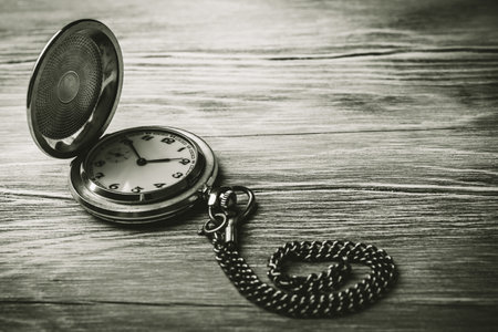 Vintage pocket watch on a wooden background, black and white photo. A vintage mechanical watch close up. Concept of passing time. Concept of old age.の写真素材