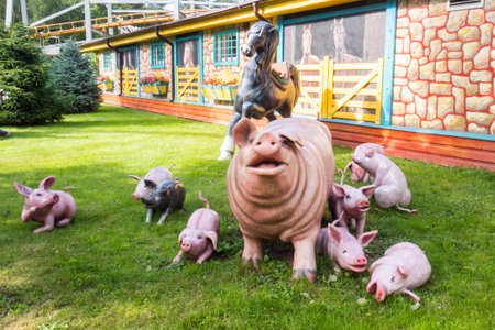 Colorful sculptures of pigs and a horse are displayed in a lively outdoor area. The unique farm scene is surrounded by greenery, creating a whimsical atmosphere during daylight.の写真素材