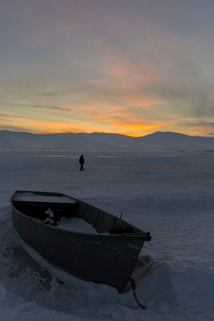 Boat on frozen Cildir lake at sunset in Ardahan, Turkey.の写真素材