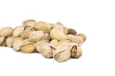 Salted pistachios are scattered on a white background, the focus is on the first plan.の写真素材