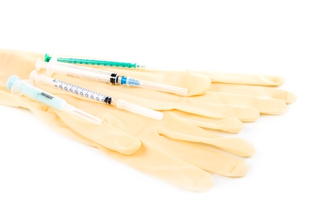 Several syringes and medical gloves on a white background.の写真素材