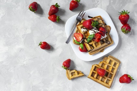 Belgium waffles with strawberries, ricotta cheese and chocolate on white plate. Top view. Copy spaceの写真素材