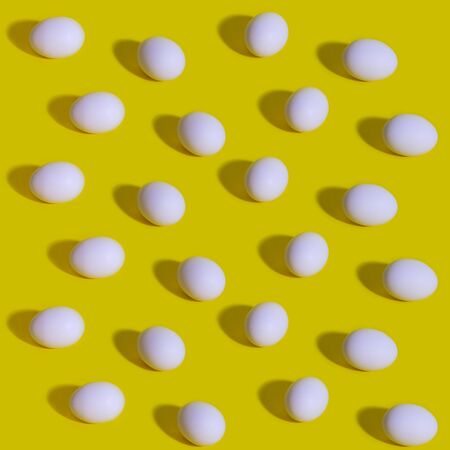 Pattern with white eggs on the pastel yellow background. Creative food minimalistic background, Easter. Natural healthy food and organic farming concept.の写真素材