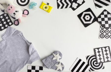 Composition with baby accessories on white background. Unisex neutral theme with baby shower or Newborn nursery concept with baby clothes, toys, Vision Development contrast cards. flat lay and top view. Copy spaceの写真素材