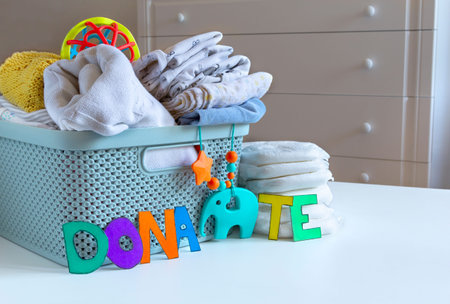 Donation box with Baby Unisex neutral clothing and donation accessories on light background