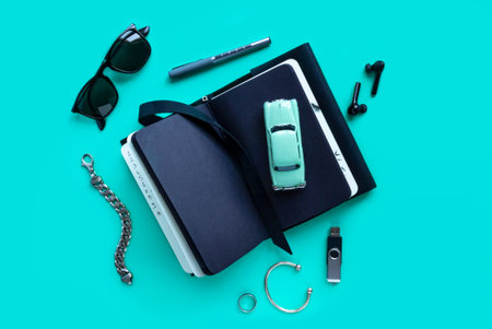 Men's accessories, notebook, airpods, sunglasses, car model on lturquoise background. Top view, flat...