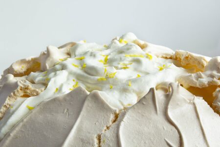 Close-up of meringue cake Pavlova with whipped cream and lemon. Crusty dessert.の写真素材
