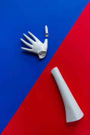 Broken plaster toy hand. Medical concept on a red-blue backgroundの写真素材