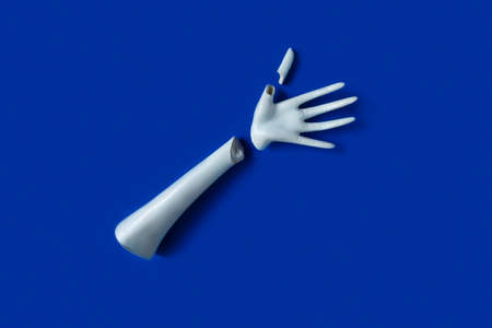 Broken white plaster hand. Medical concept on a blue background. Horizontal shotの写真素材