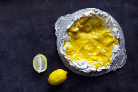 Homemade meringue basis for cake Pavlova with lemon curd. Crusty dessert on the black backgroundの写真素材