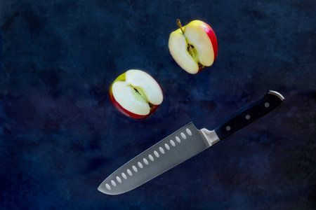 Red apple slices cut with fruit Knife on dark background. Food Levitation and copy space