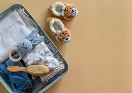 Donation box with Baby Unisex neutral clothing and donation accessories on beige background. Flat lay and copy spaceの写真素材