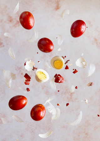 Red natural dye easter eggs flying with feathers on pastel beige background. verticalの写真素材