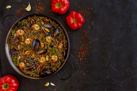 Black paella with seafood and squid ink on a black background. Copy spaceの写真素材