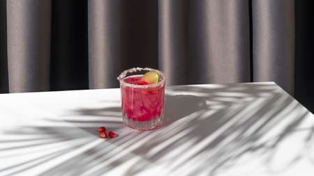 Summer cocktail with pomegranate and ice with palm shadowの写真素材