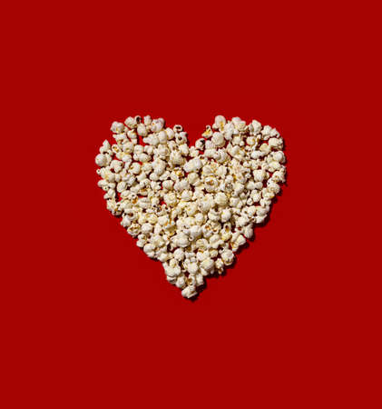 Heart made of popcorn on red backgroundの写真素材