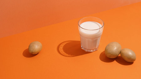 A glass of potato milk on the table with potatoes