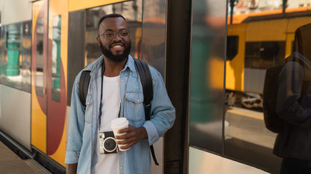 Smiling adult tourist man with coffee at train stationの写真素材