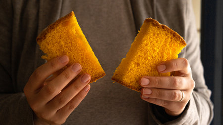 Two pieces of portuguese spongecake in handsの写真素材
