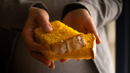 Two pieces of portuguese spongecake in handsの写真素材