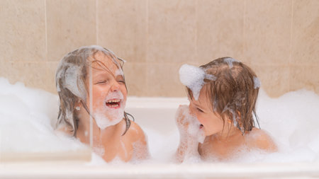 Cute sisters girls in bath with Soap Foamの写真素材