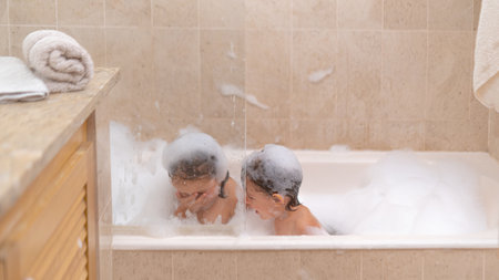 Cute sisters girls in bath with Soap Foamの写真素材