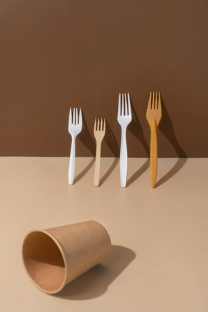 Eco friendly forks and cup on a beige and brown background.