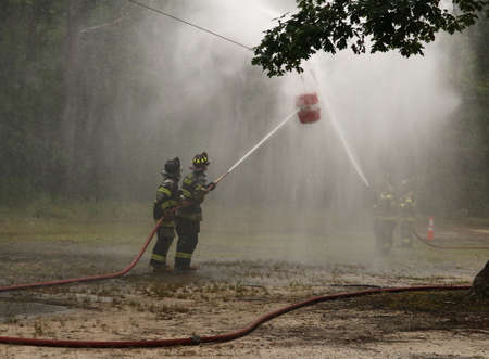 BUENA VISTA, NEW JERSEY USA  JULY 2, 2016  Firemen in a competition spraying a firehouseのeditorial素材