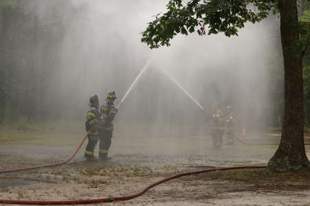 BUENA VISTA, NEW JERSEY USA  JULY 2, 2016  Firemen in a competition spraying a firehouse.のeditorial素材