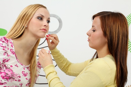 Makeup artist applying makeup on attractive young woman face. の写真素材