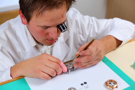 Watchmaker in his workshop repairing a wrist watch. Intentional shallow depth of fieldの写真素材